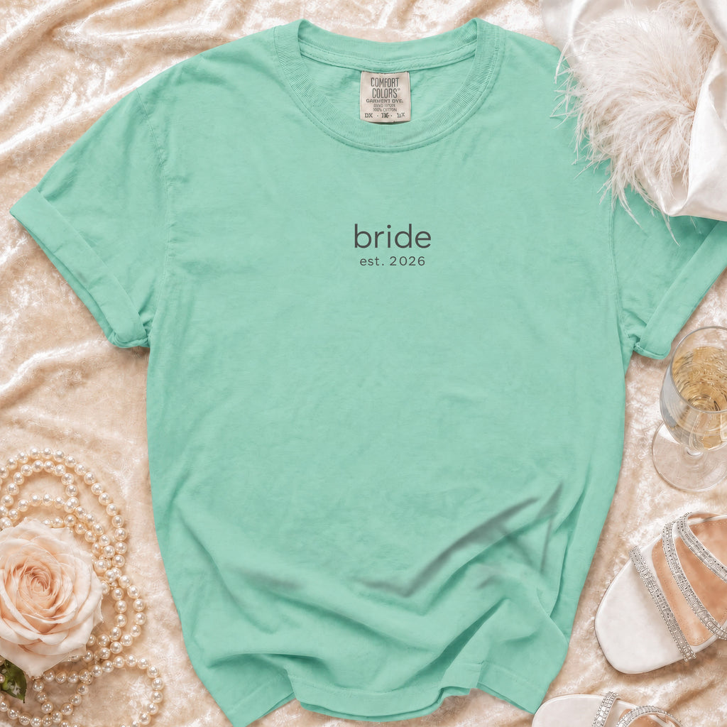 Mint Comfort Colors t-shirt with "bride est. 2026" text, flat lay.