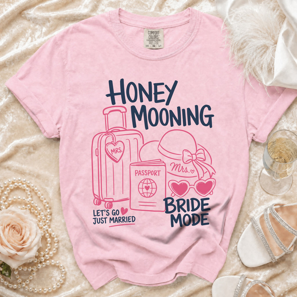 Pink t-shirt with "Honey Mooning Bride Mode" text and travel icons.