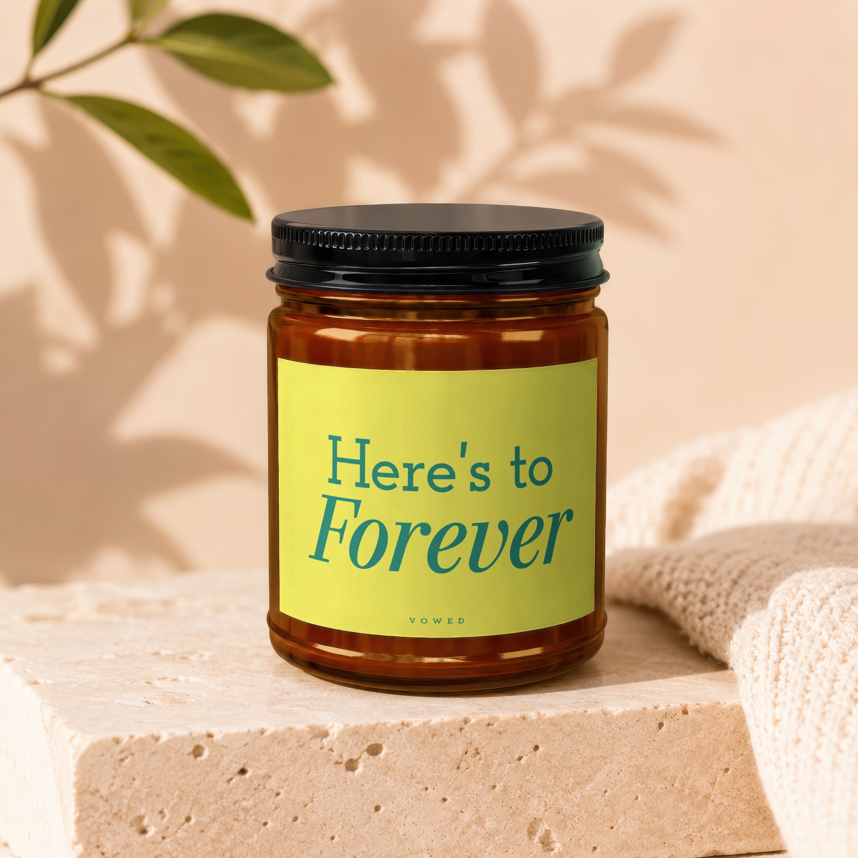 Amber jar candle with a light green label reading "Here's to Forever" and "VOWED".