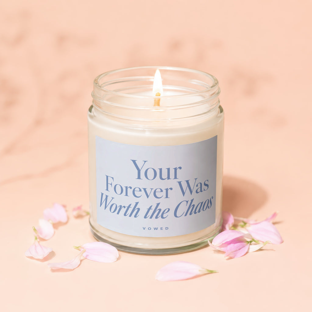 Candle with text "Your Forever Was Worth the Chaos VOWED" surrounded by pink petals.