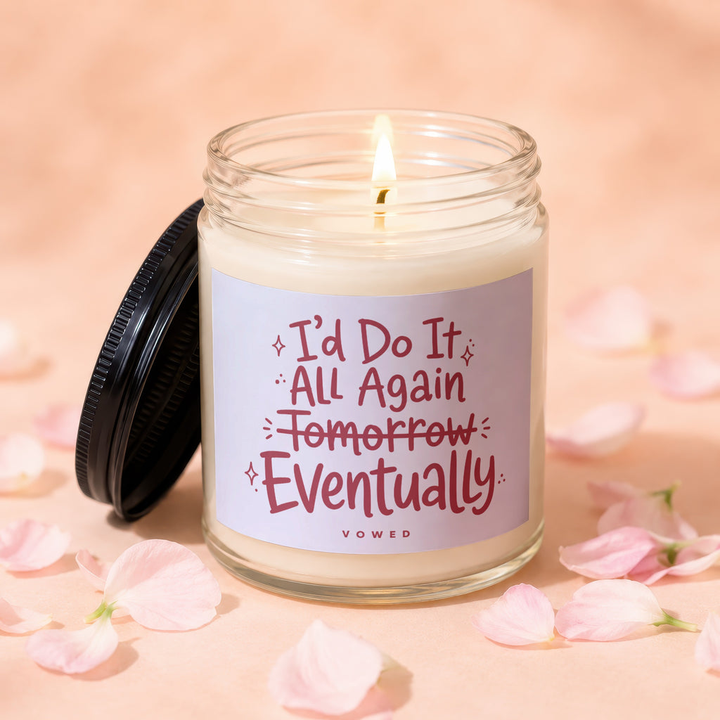 Glass jar candle with a lit wick and a black lid, saying "I'd Do It All Again Tomorrow Eventually".
