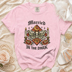 Pink t-shirt with skull, moth, candles, roses, rings saying "Married In The Dark".
