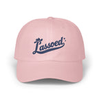 A light pink baseball cap featuring embroidered dark blue text that reads Lassoed.