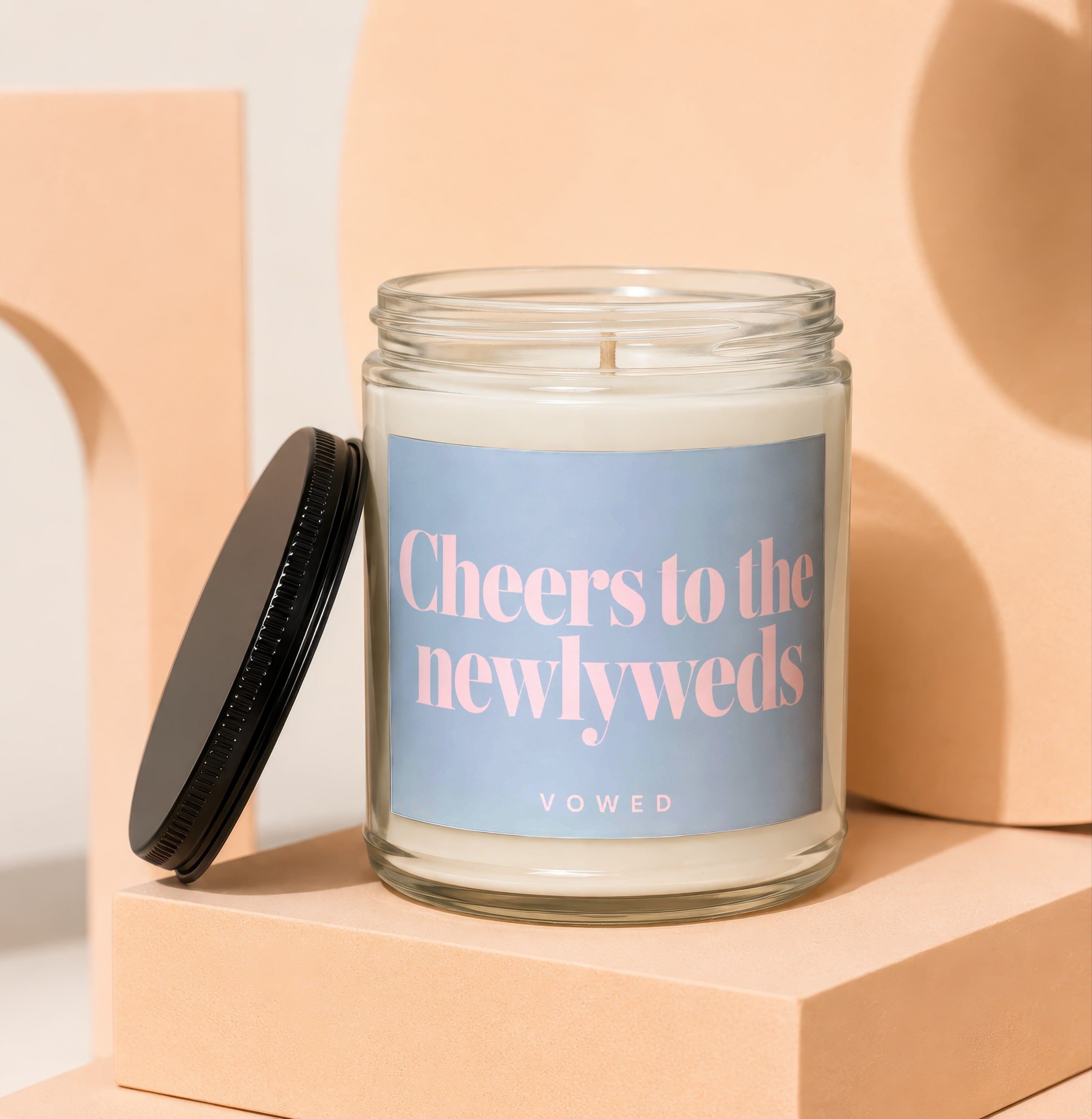 Glass candle with black lid, says "Cheers to the newlyweds" and "VOWED".