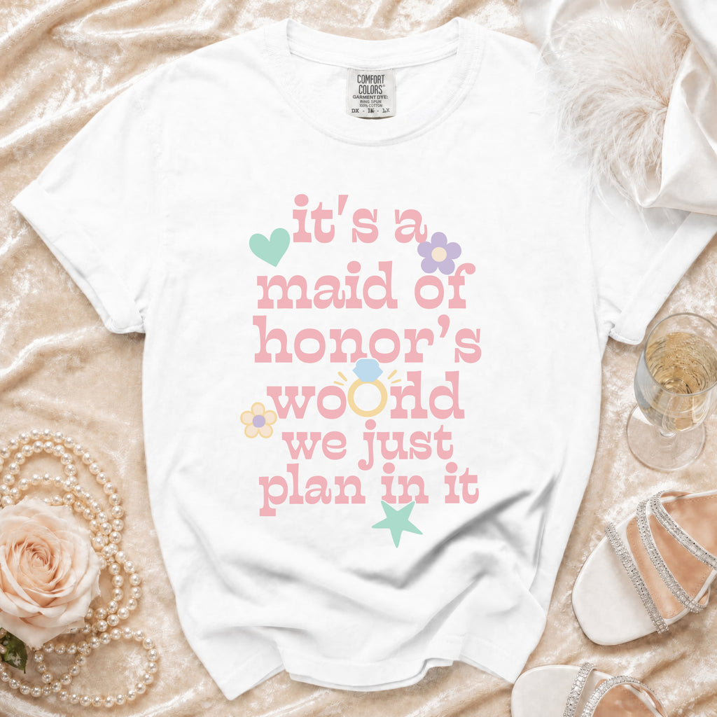 White t-shirt with pink text saying "it's a maid of honor's world we just plan in it".