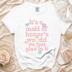 White t-shirt with pink text saying "it's a maid of honor's world we just plan in it".