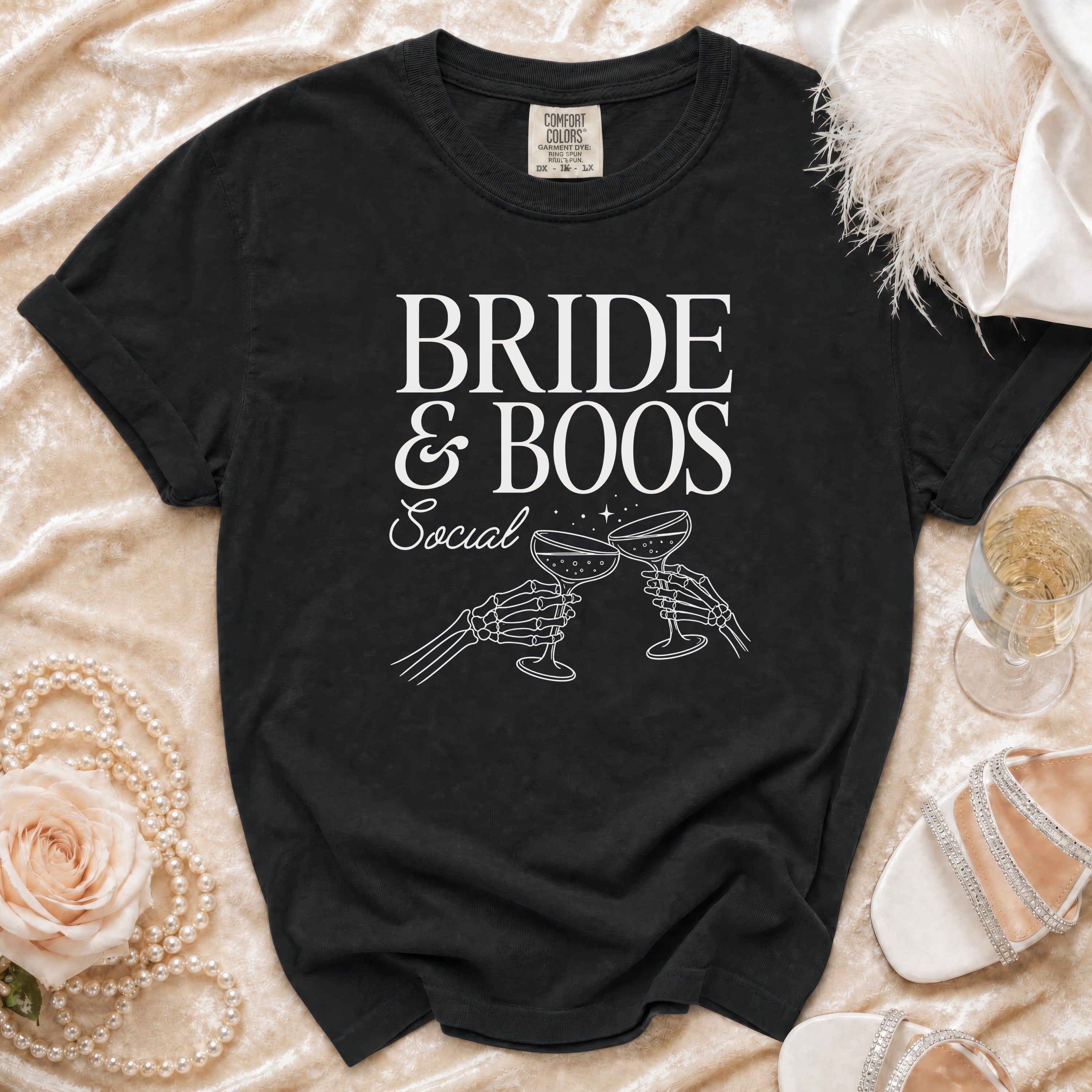 Black t-shirt with "BRIDE & BOOS Social" text and skeleton hands toasting champagne.