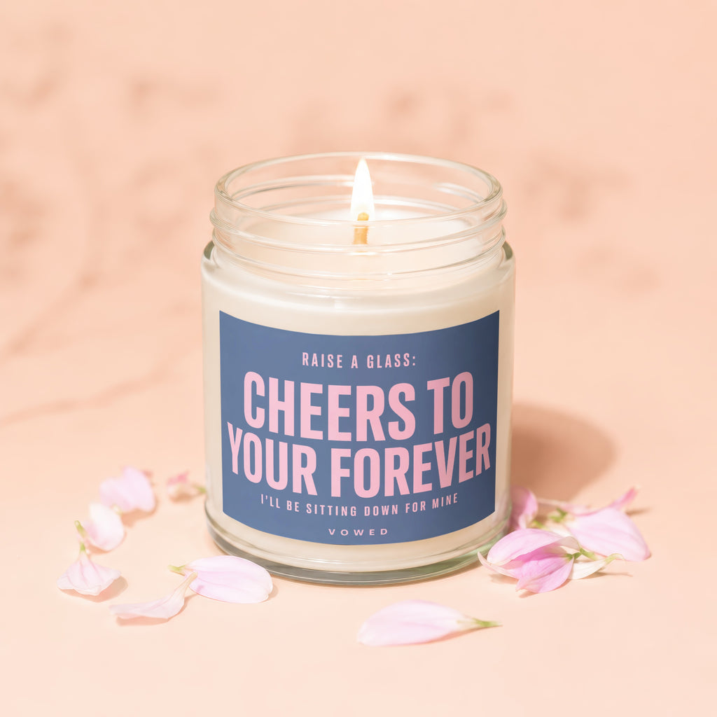 Candle with label "Cheers to Your Forever" surrounded by pink flower petals.
