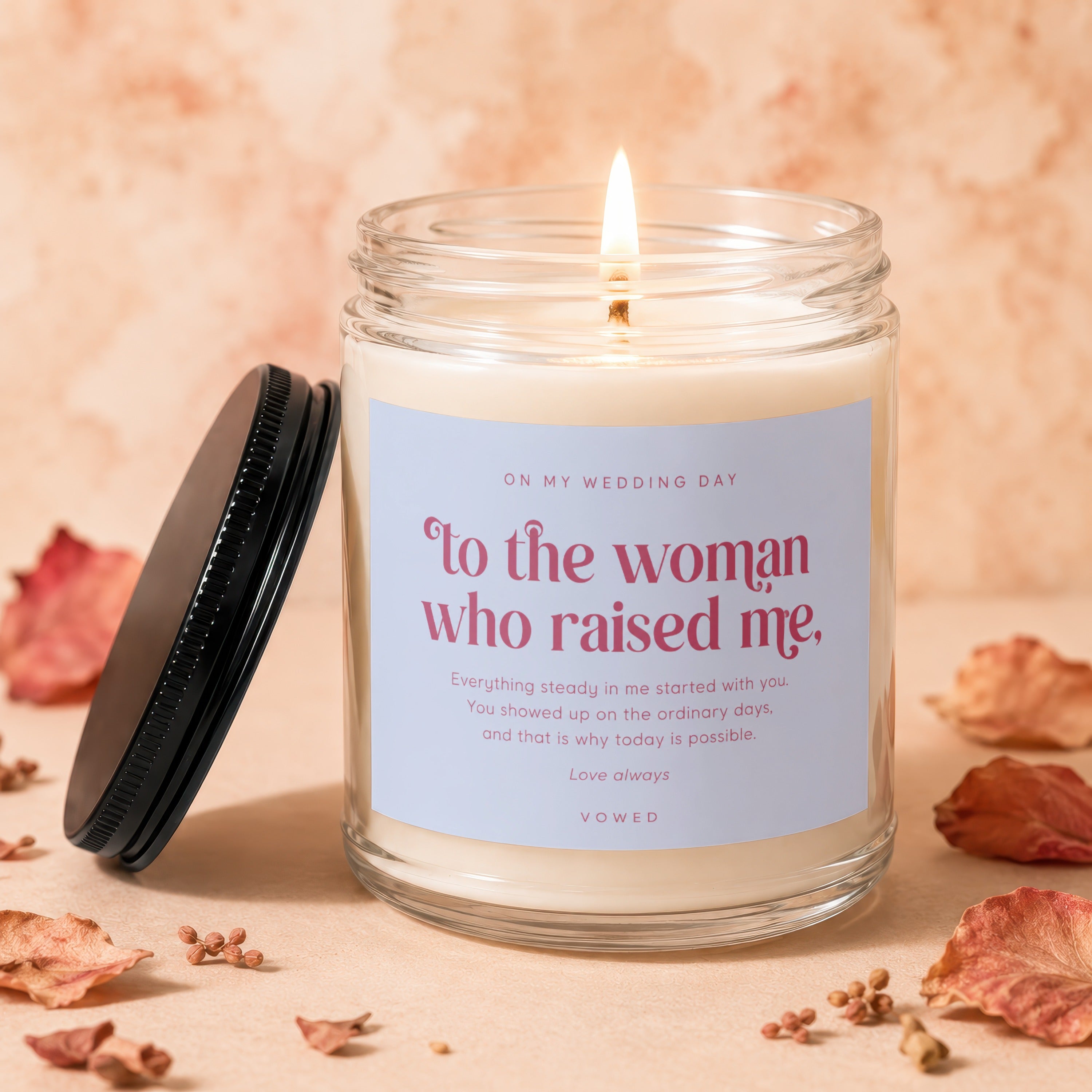 Lit candle in glass jar with label "To the woman who raised me" for wedding day.