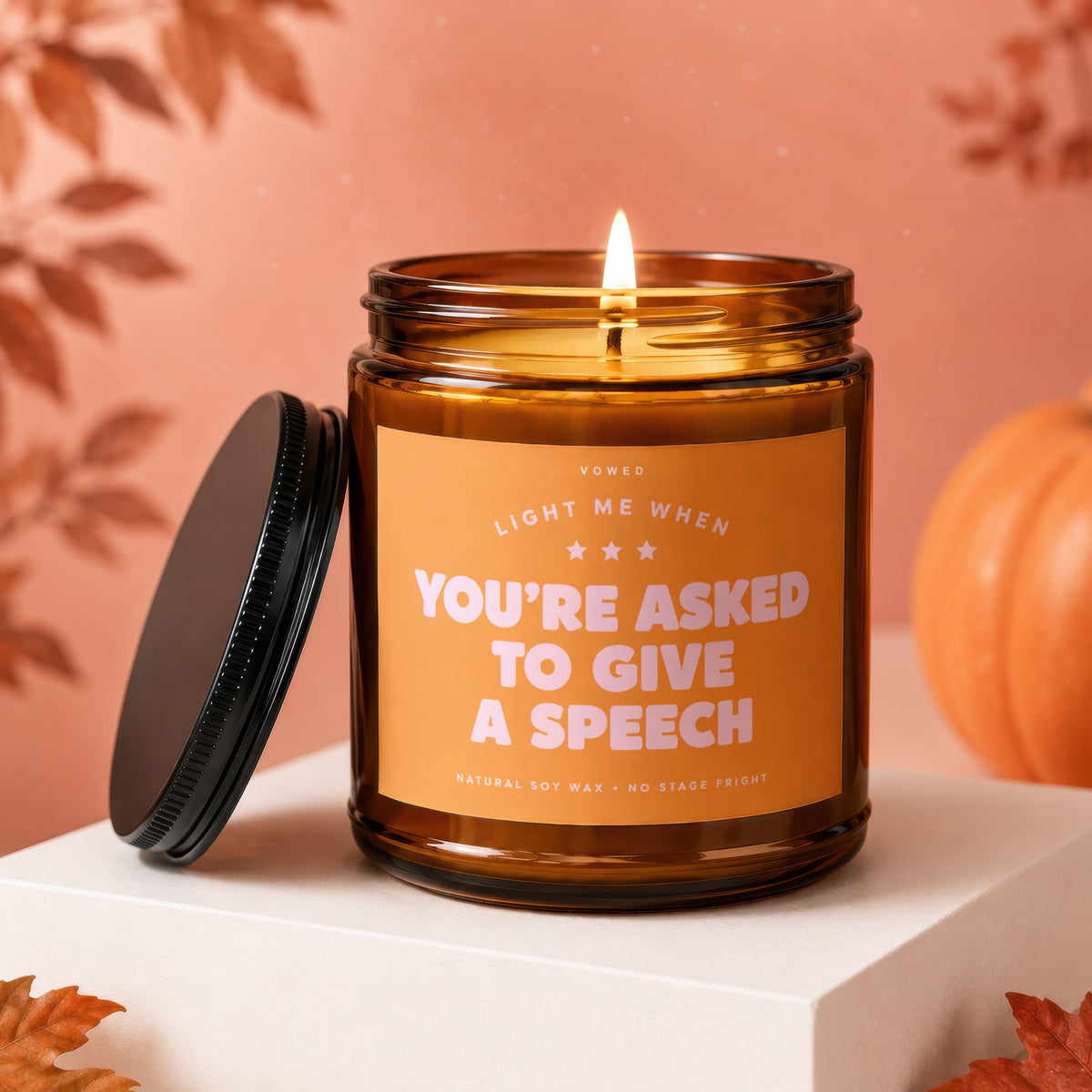 Amber glass candle with orange label reading "Light me when you're asked to give a speech."