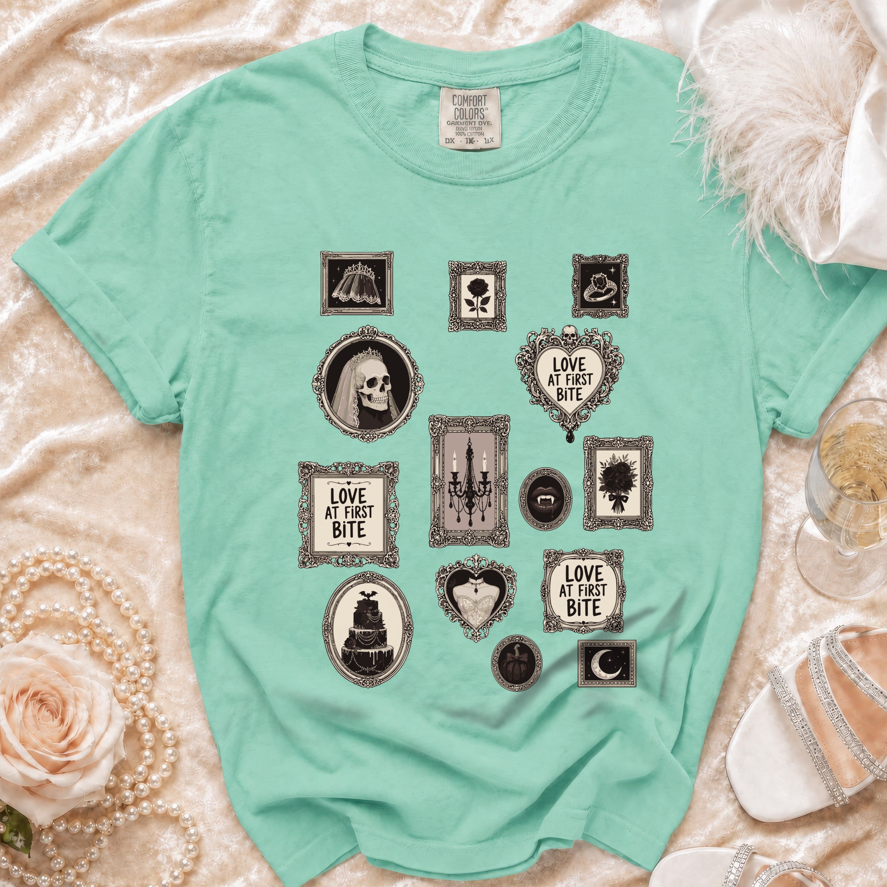 Mint green t-shirt with framed gothic illustrations, including skulls, bats, and text.