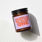 Amber jar candle with purple label reading "Two brides are better than one."