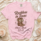Pink t-shirt with "Reckless in Texas" and "Olivia's Bach Austin, TX Summer 2026".