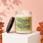 Glass jar candle with "Ringed and Radiant Vowed" text on a light green label.