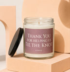 Glass candle with black lid and a label reading "THANK YOU FOR HELPING US TIE THE KNOT VOWED".