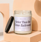 Clear glass candle with black lid reads "Smells like Better Than the Venue Bathrooms. Vowed."