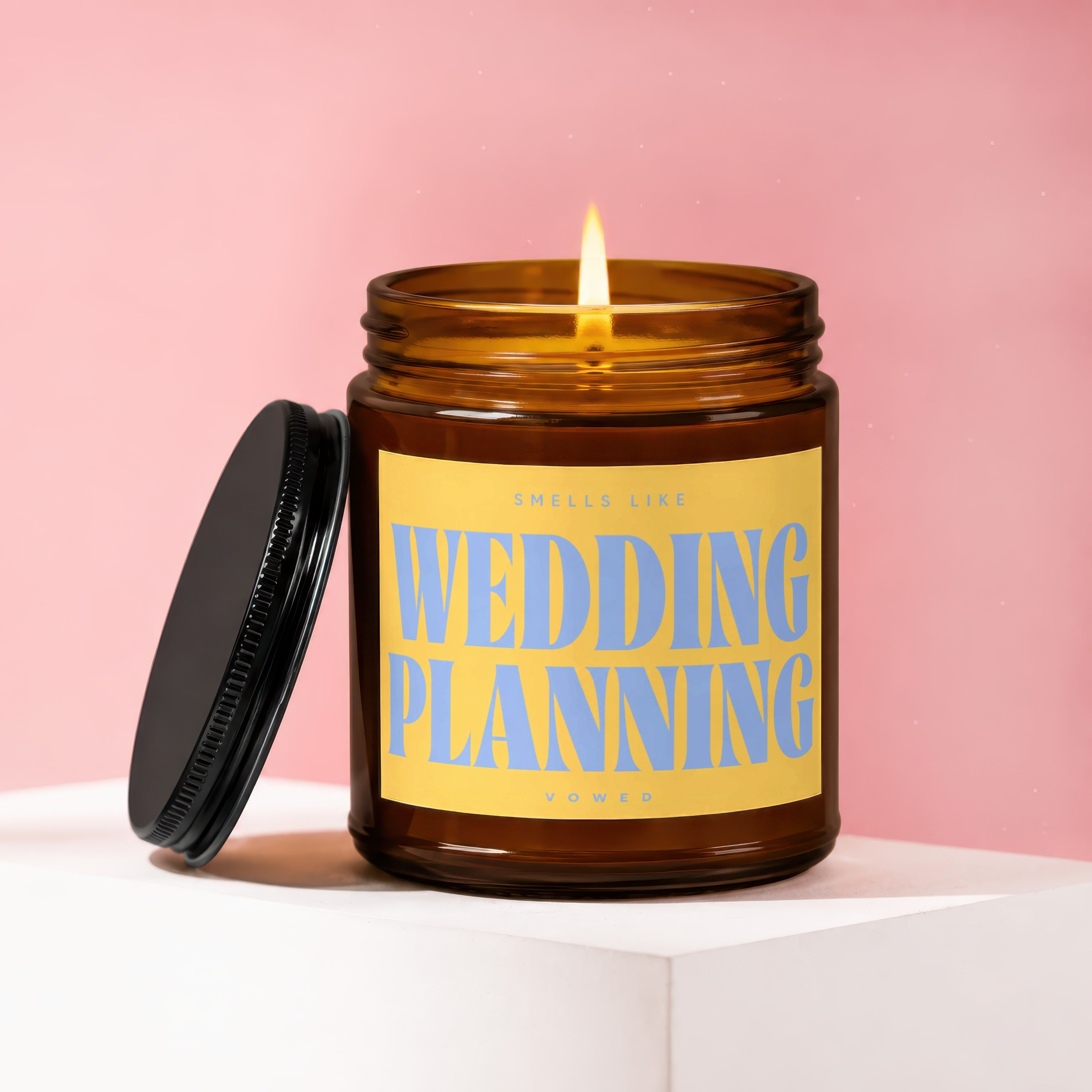 Amber jar candle with lit flame, reads "Smells Like Wedding Planning"
