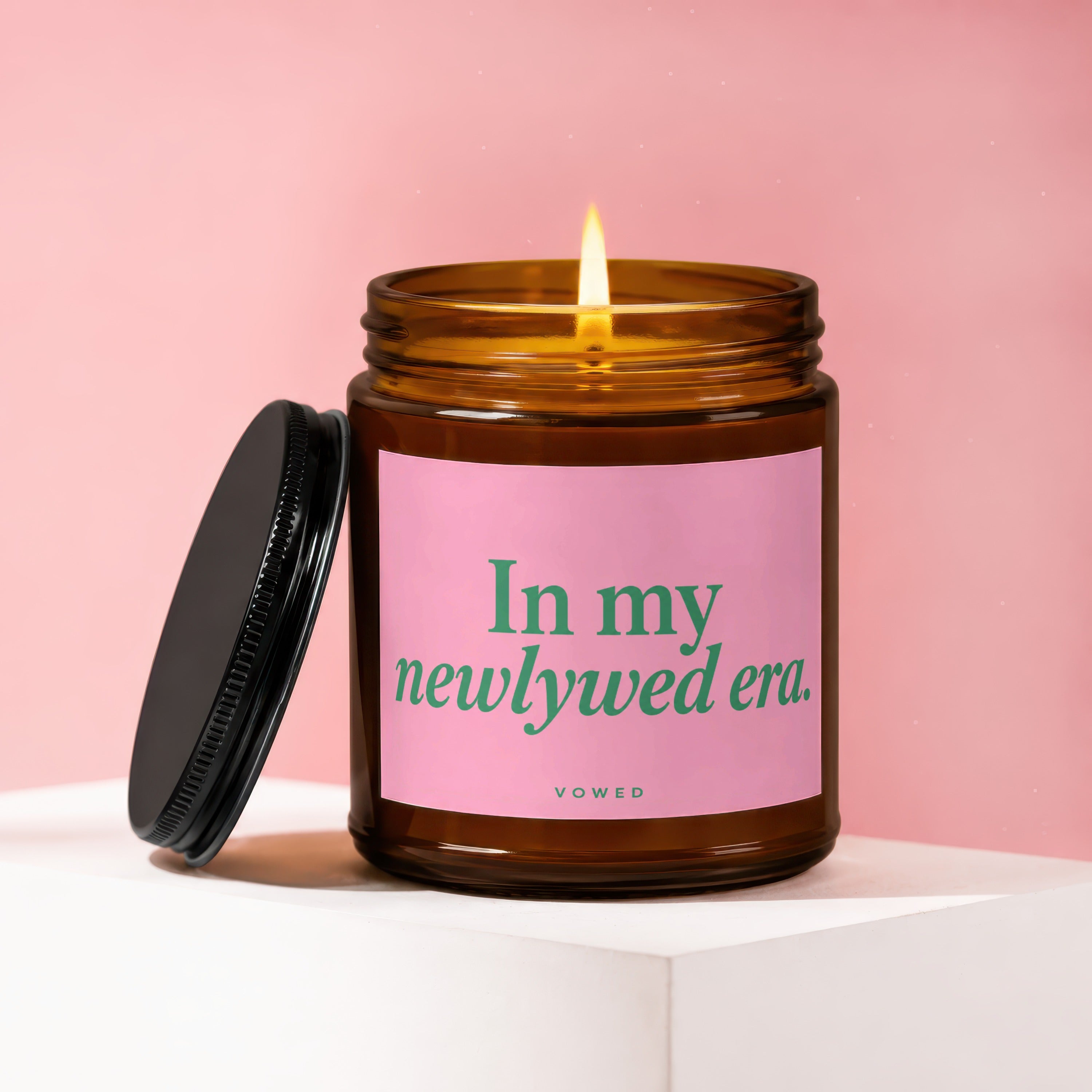 Amber candle in glass jar with pink label reads "In my newlywed era."