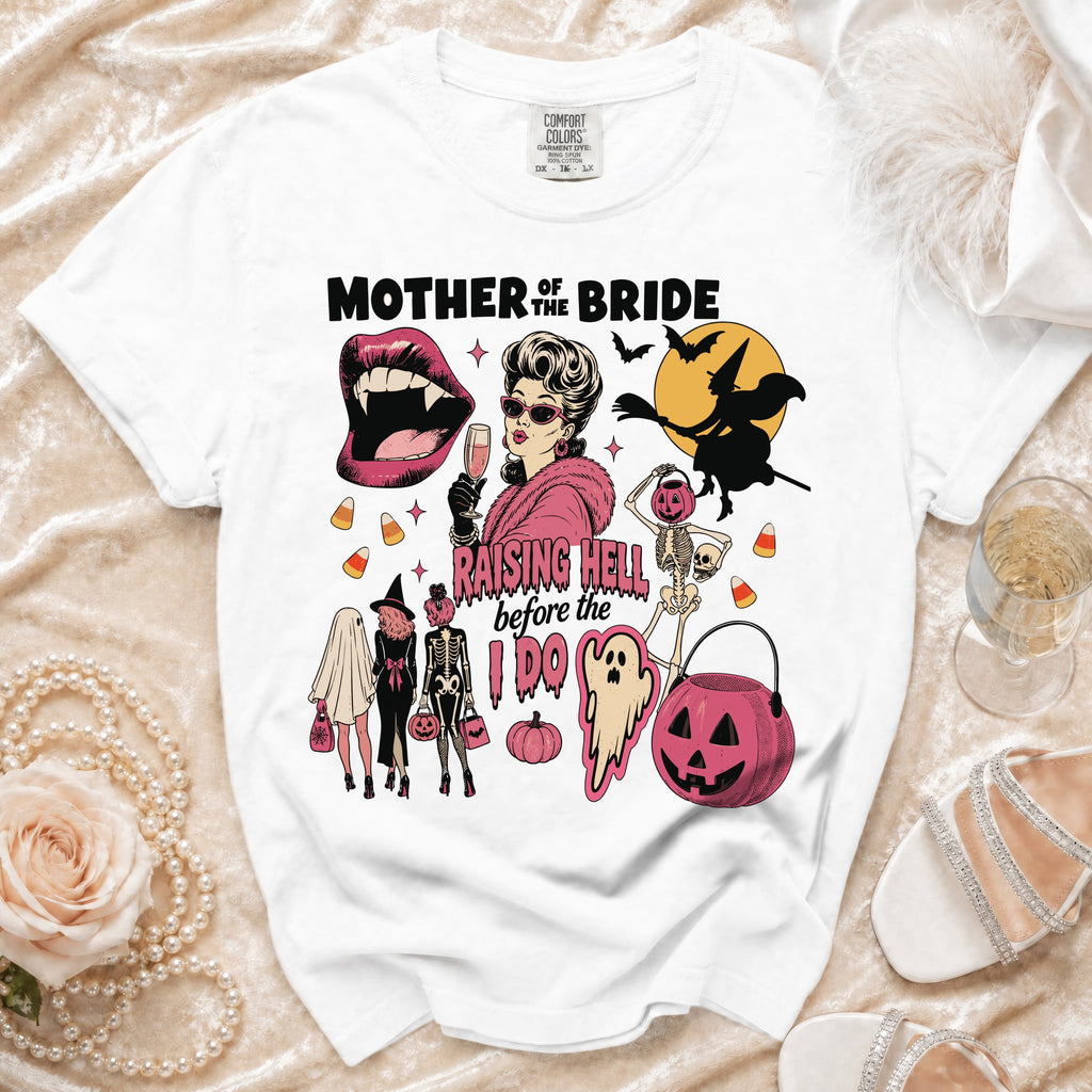 White t-shirt graphic "Mother of the Bride Raising Hell Before I Do" with Halloween imagery.