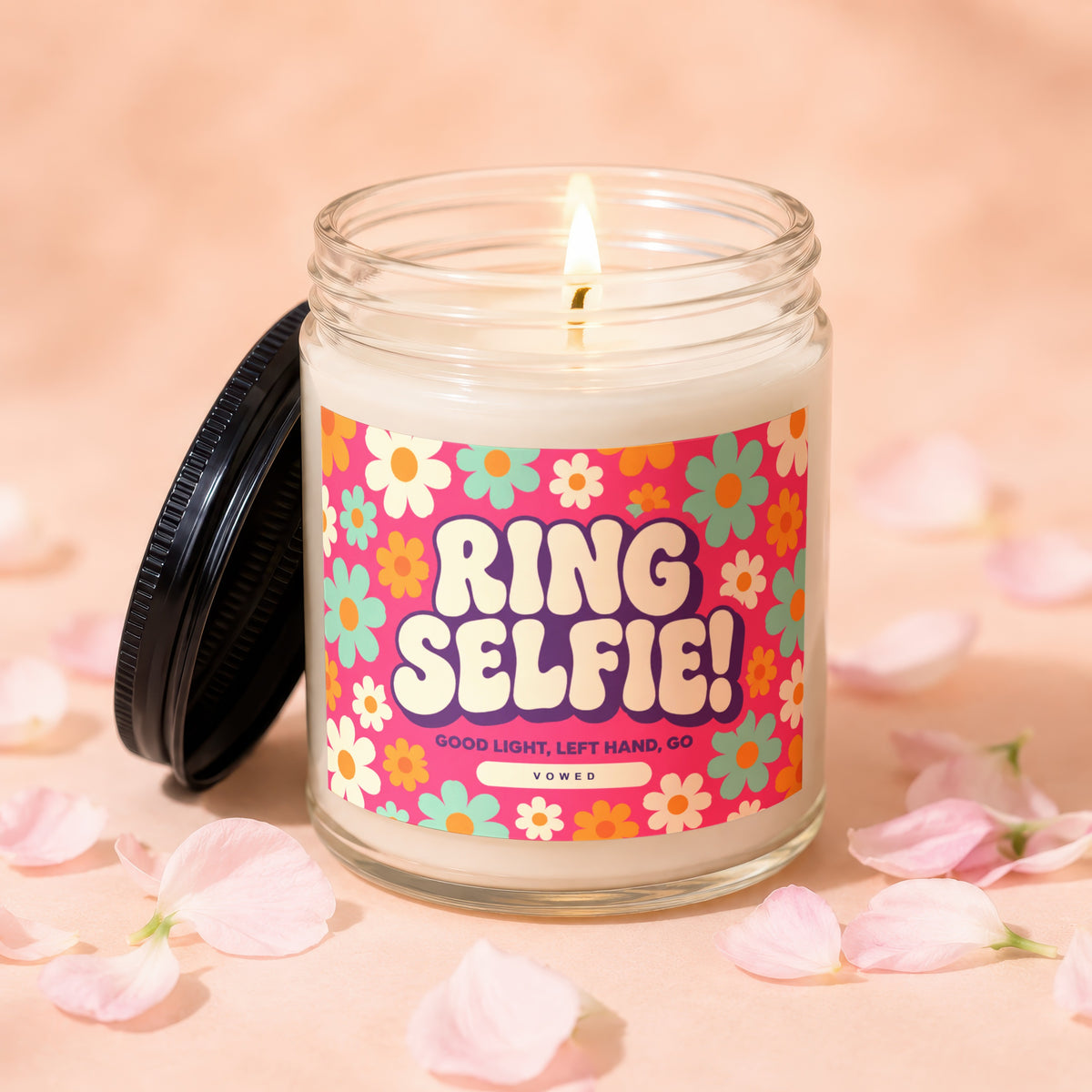 Glass jar candle with a "Ring Selfie!" label, surrounded by pink petals.