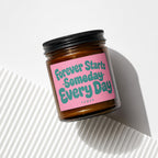 Amber jar candle with pink label reading "Forever Starts Someday Every Day".