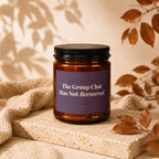 Amber jar candle with purple label reading "The Group Chat Has Not Recovered."