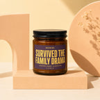 Brown candle with purple label reading "Survived the Family Drama."