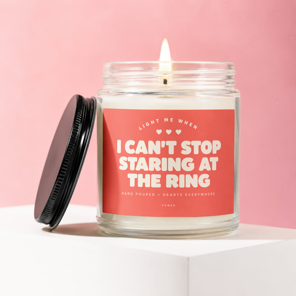 Candle with coral label reading "I CAN'T STOP STARING AT THE RING"