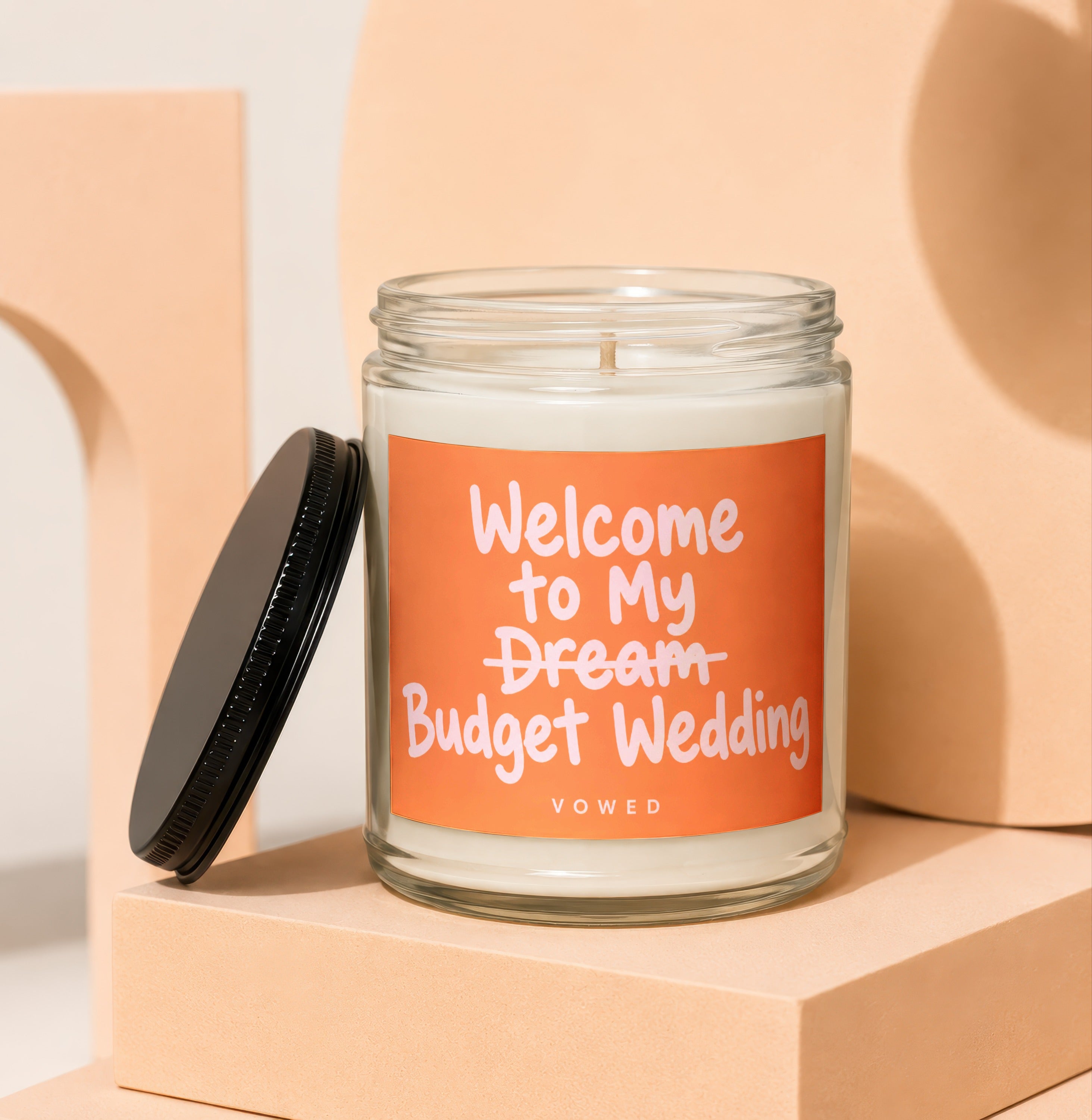Candle with orange label reading "Welcome to My Dream Budget Wedding VOWED".