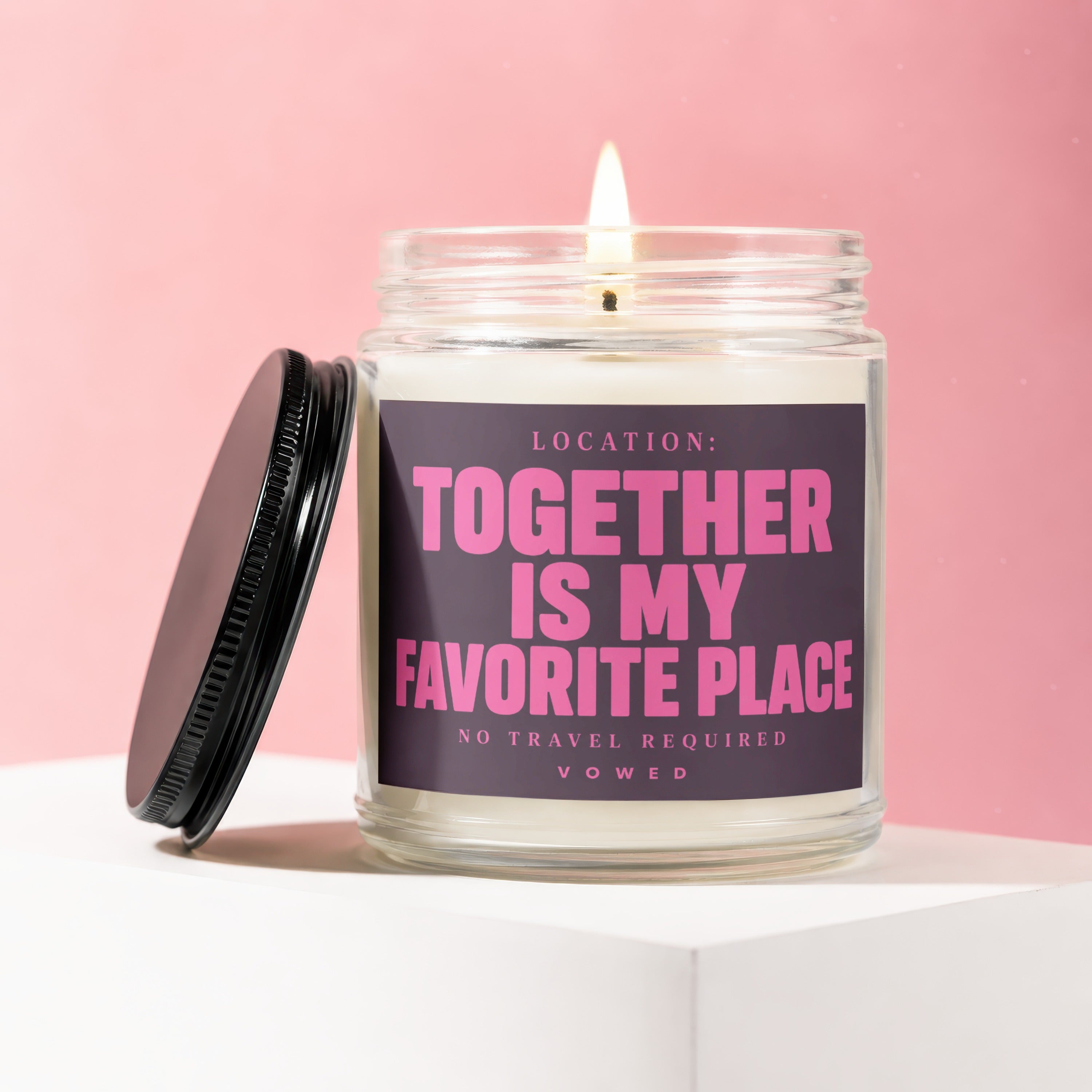 Glass jar candle with lit wick and black lid labeled "Location: Together Is My Favorite Place".