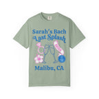 Sarah's Bach Last Splash Bride graphic with rings, champagne, and hibiscus on sage green t-shirt.