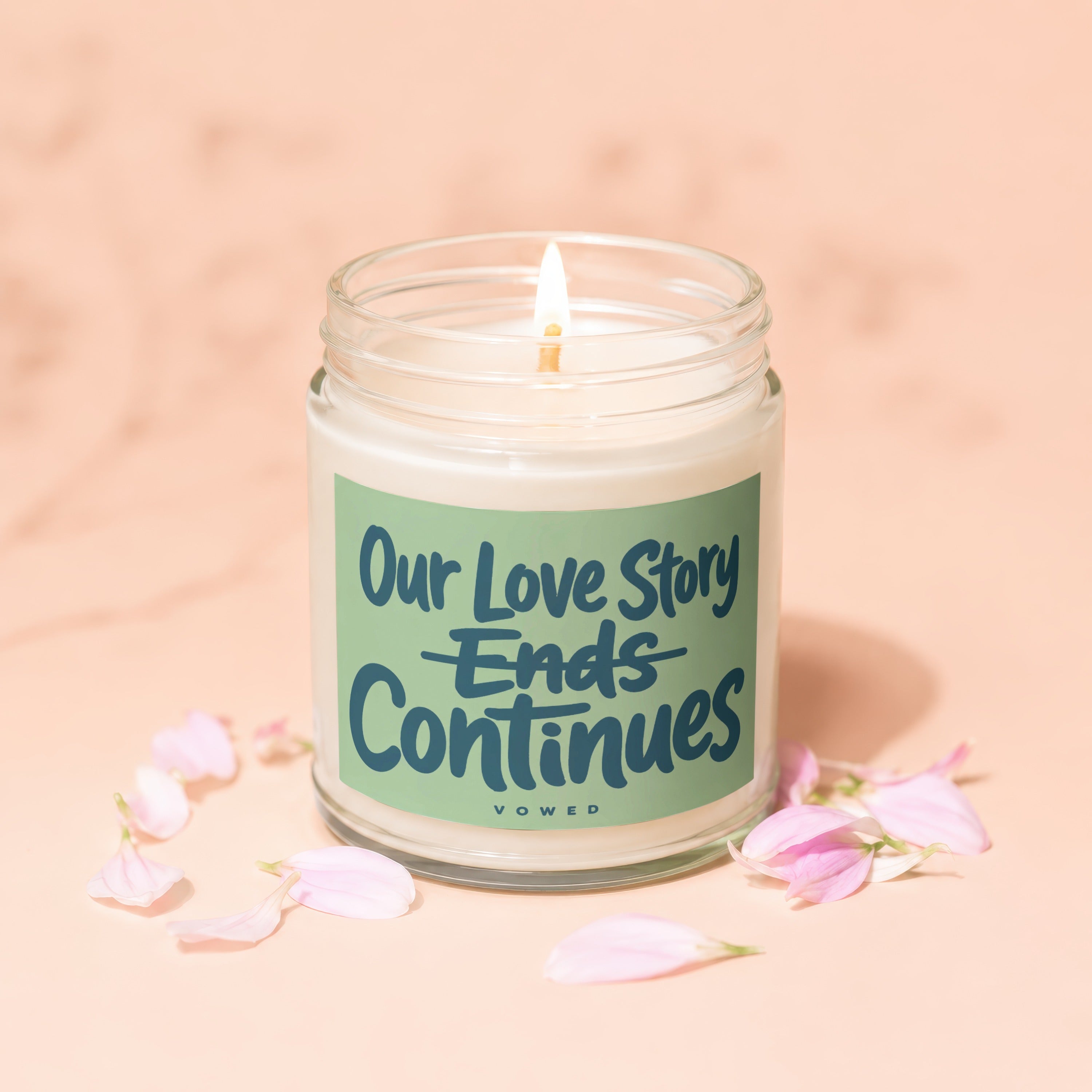 Glass jar candle with green label that reads "Our Love Story Ends Continues" and "VOWED".