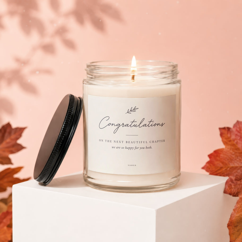 Glass candle with lit wick, "Congratulations" label, and black lid nearby.