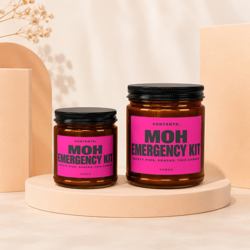 Two MOH Emergency Kit candles with pink labels, listed as safety pins, snacks, this candle.