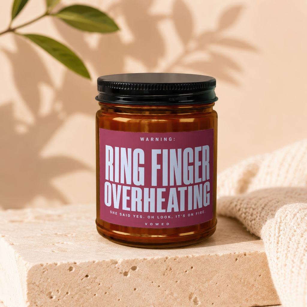 Amber jar candle with label saying "Ring Finger Overheating" and "She Said Yes."