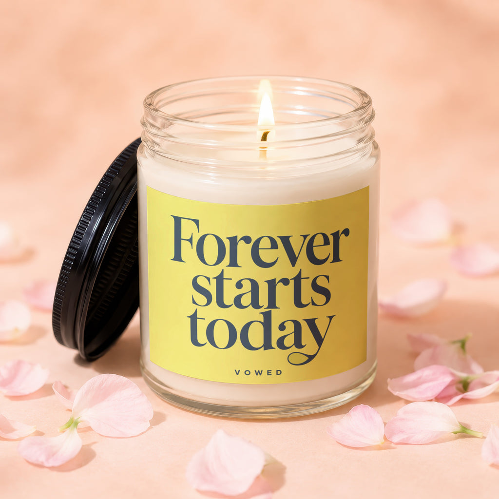 Lit candle in a glass jar with lid off, reads "Forever starts today"