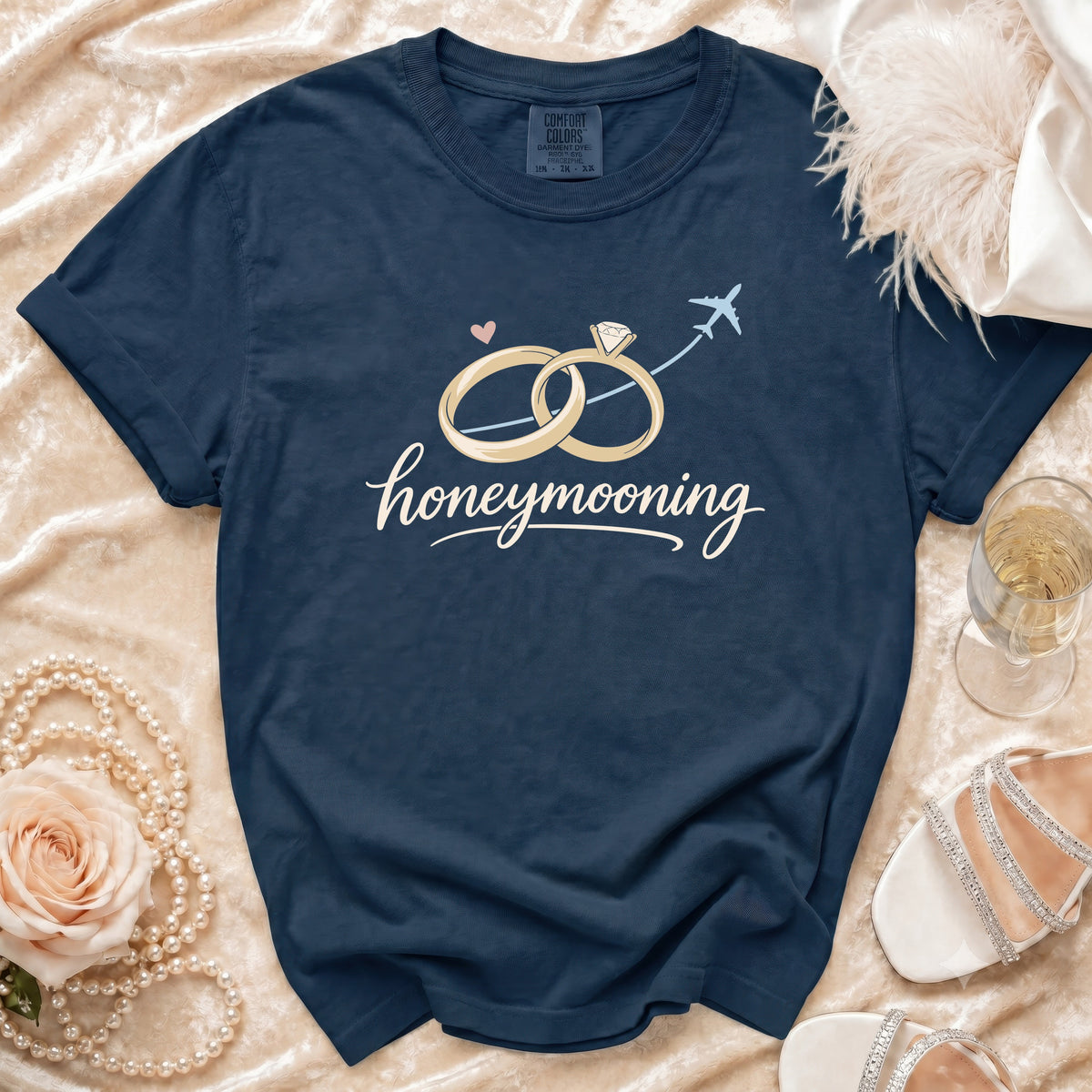Navy t-shirt with "honeymooning" text, rings, plane, and heart graphic.