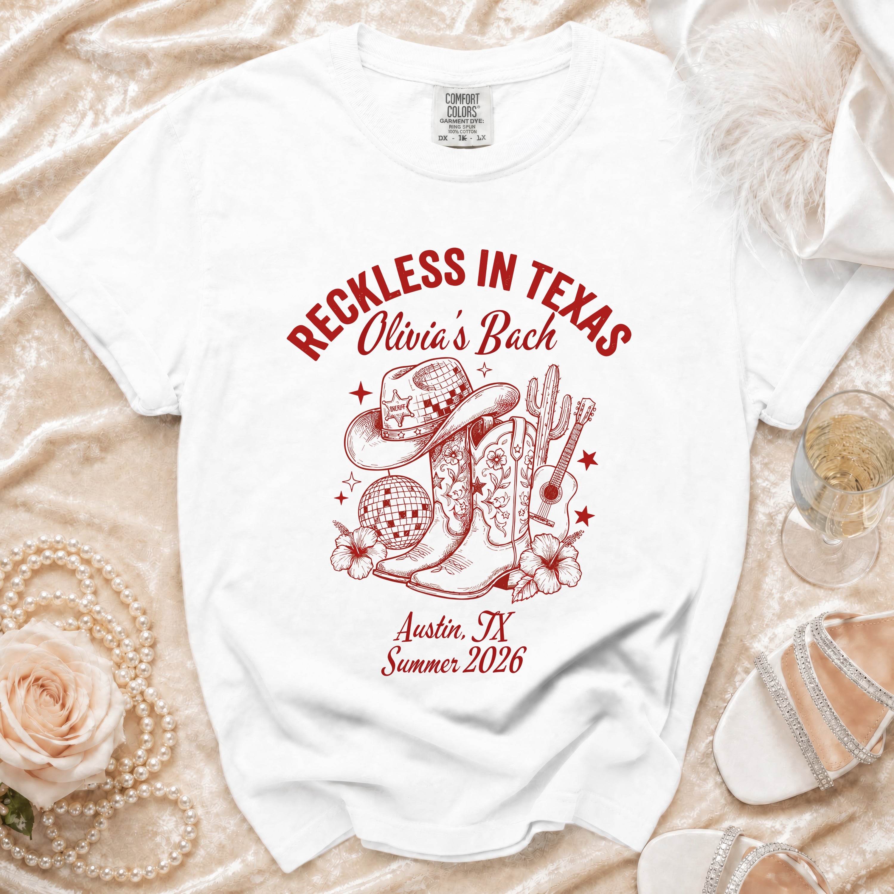 White t-shirt with "Reckless in Texas" design featuring boots, hat, and disco ball.