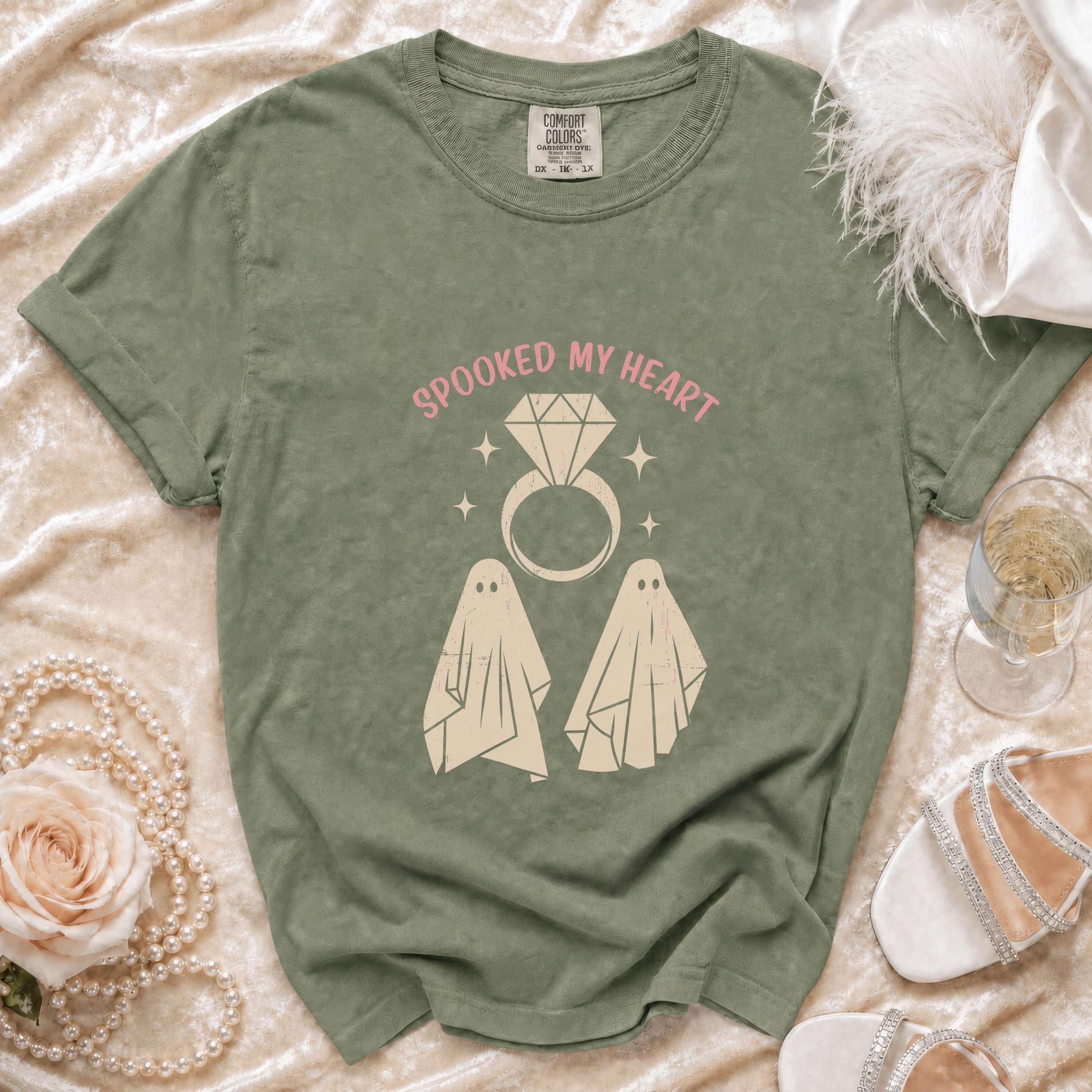 Olive green t-shirt with "Spooked My Heart" text, diamond ring, and ghost graphics.
