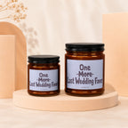 Two amber glass candles with black lids, labeled "One More Last Wedding Favor".