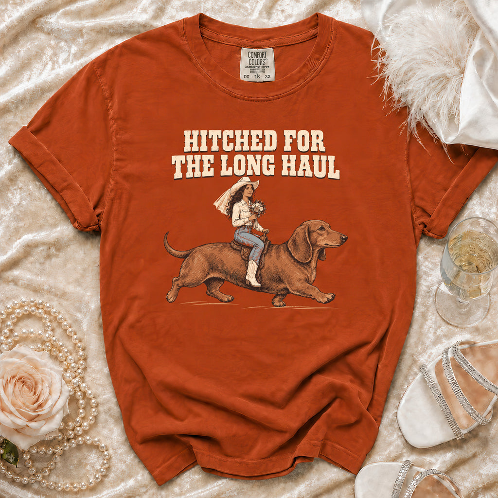 Orange t-shirt with graphic of bride riding dachshund, text "Hitched for the Long Haul".