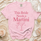 Pink t-shirt with "This Bride Needs a Martini" text and martini glass graphic.