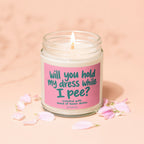 Candle with pink label asking "will you hold my dress while I pee?"