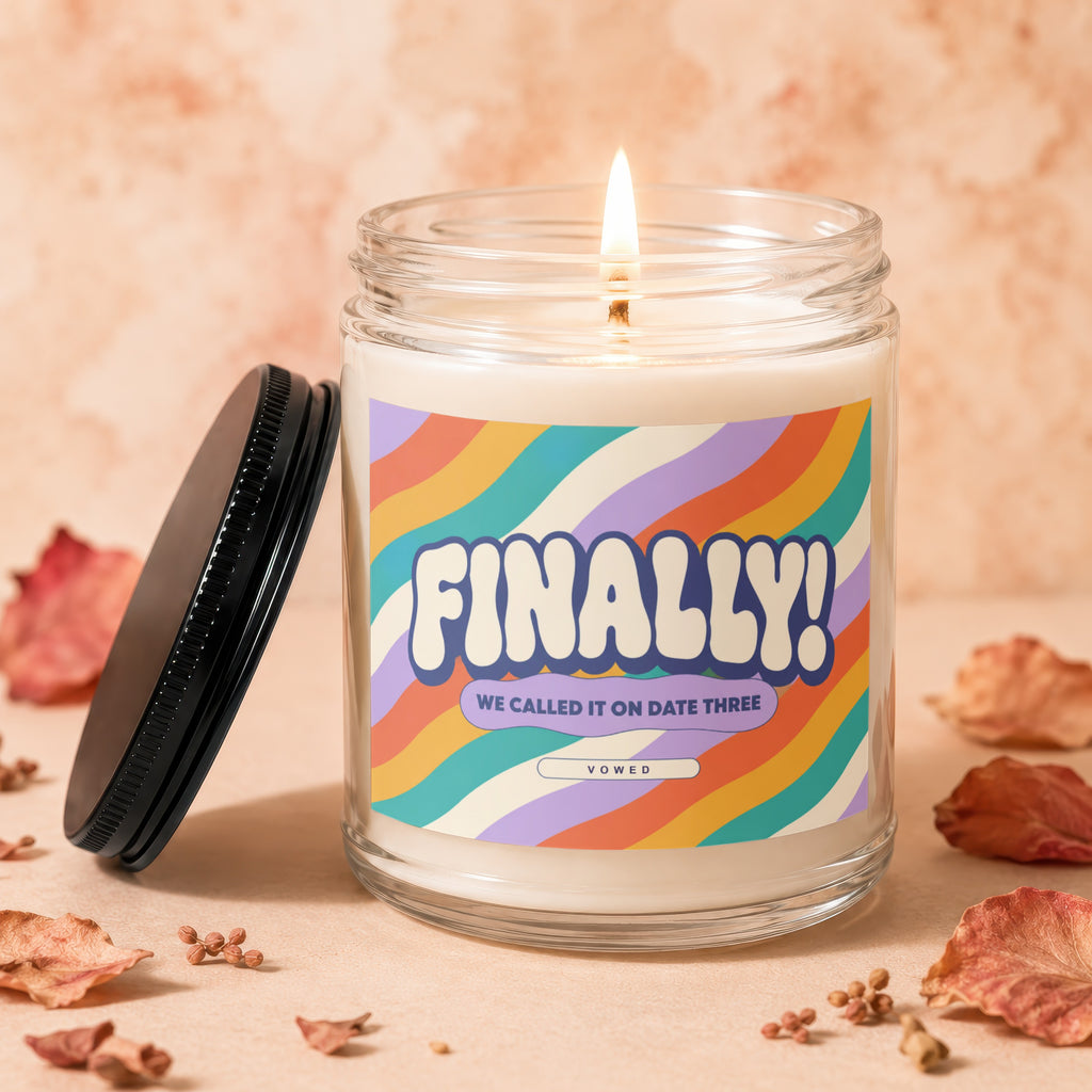 Glass candle with colorful waves label reading "FINALLY! WE CALLED IT ON DATE THREE VOWED".