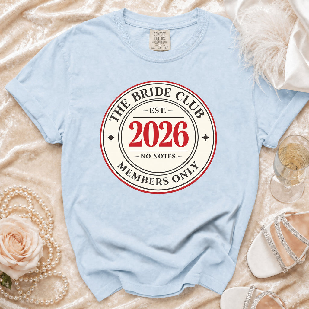 Light blue t-shirt with "The Bride Club Est. 2026 Members Only" design.