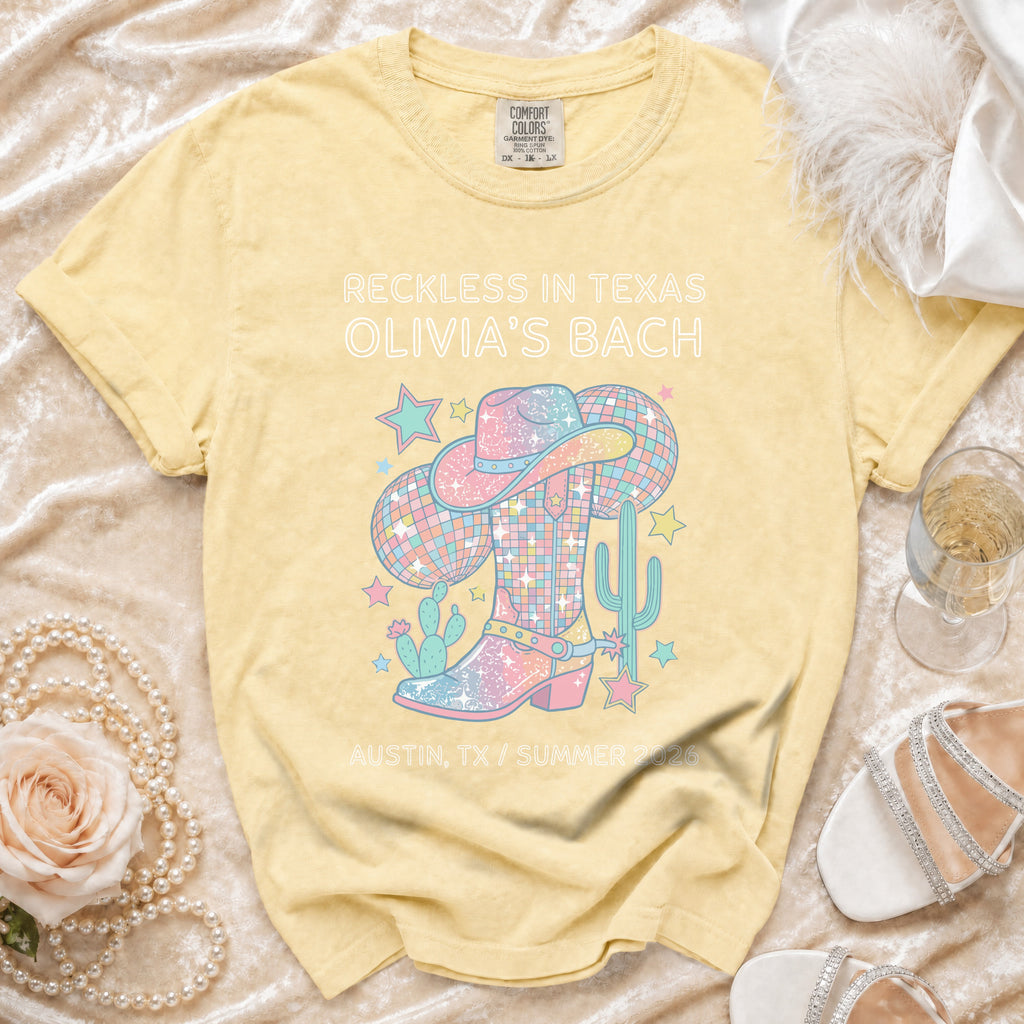 Yellow t-shirt with "Reckless in Texas Olivia's Bach" and pastel cowboy boot graphic.