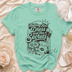 Mint green t-shirt with "Holding Her Dress and Her Secrets" graphic.