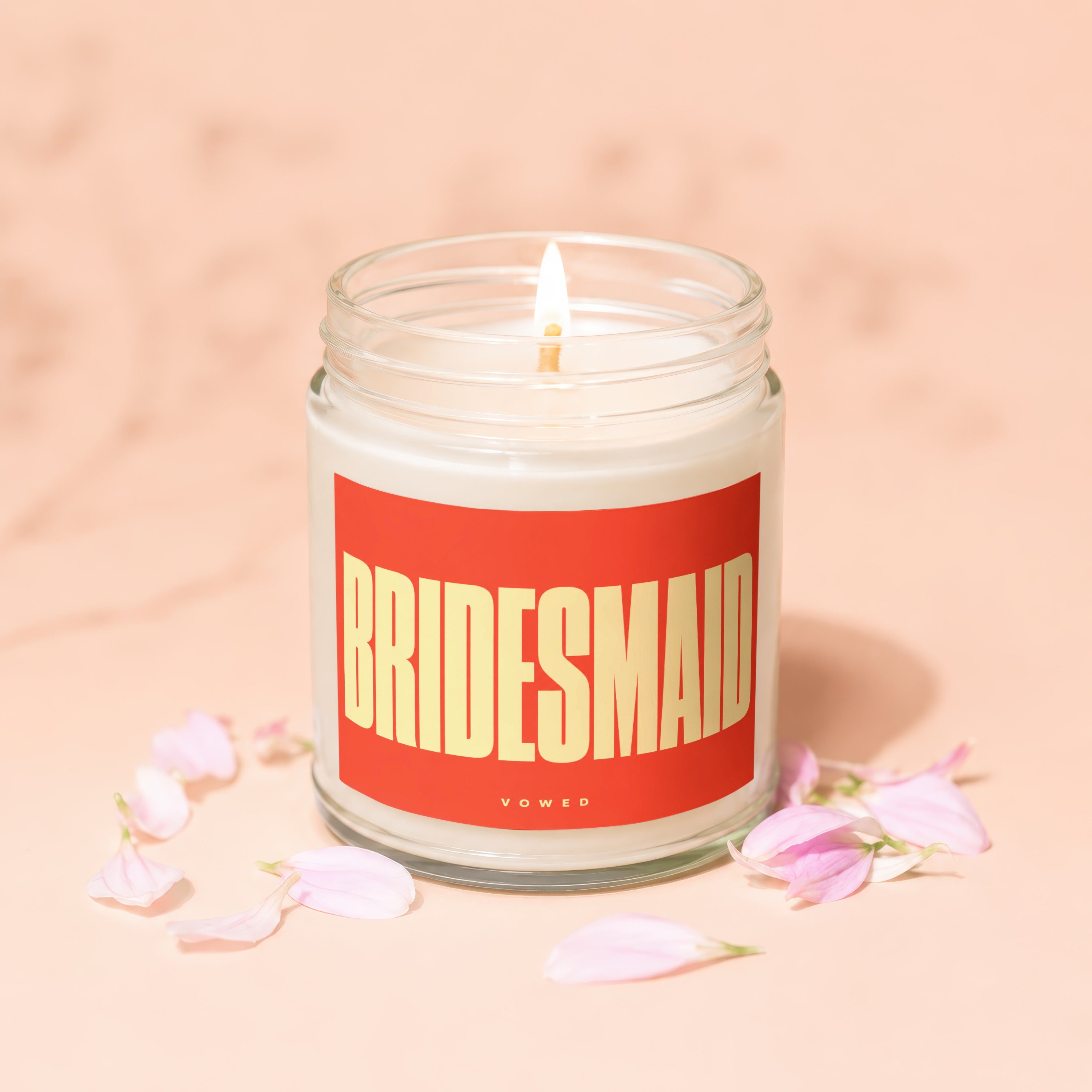 Candle labeled "BRIDESMAID" with the word "vowed" below, surrounded by pink flower petals.