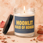 Glass candle with lit wick, lid off, labeled "Moonlit Maid of Honor".