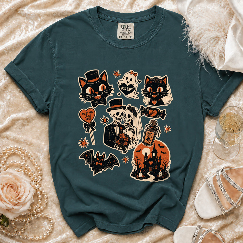 Teal t-shirt with Halloween-themed graphic featuring cats, skeletons, and a haunted house.